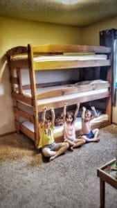 three kids in front of triple bunk bed