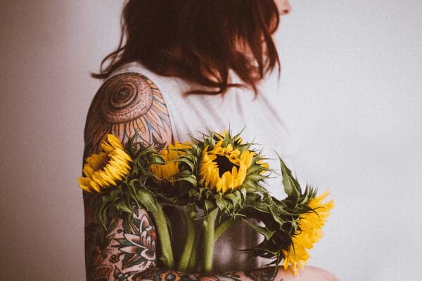 woman with shoulder tattoo holding flowers