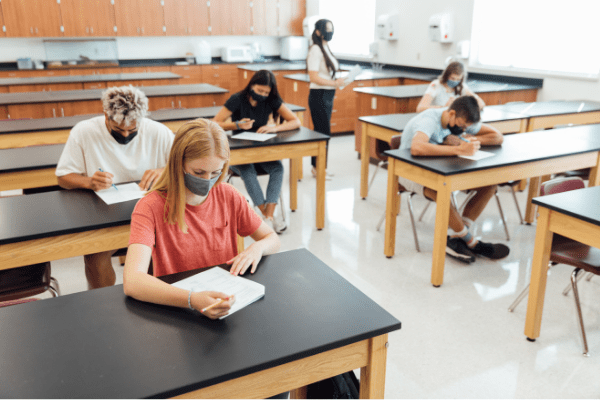 masked teacher and students in class