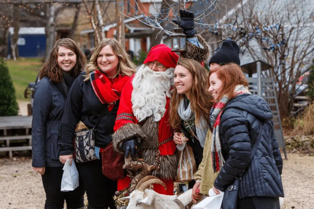 Women standing next to Jultomte the Christmas gnome and his pet goat during God Jul Holiday Celebration in Stockholm, WI