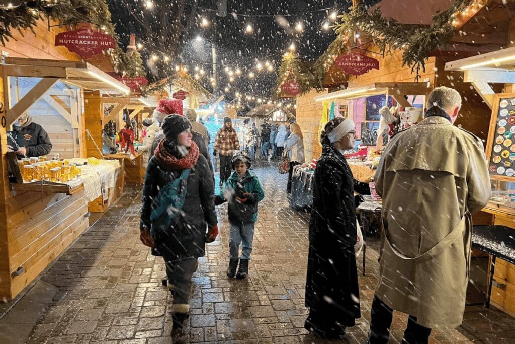 People walking around the Kriskindlmarkt on a snowy night in Sparta, Wisconsin