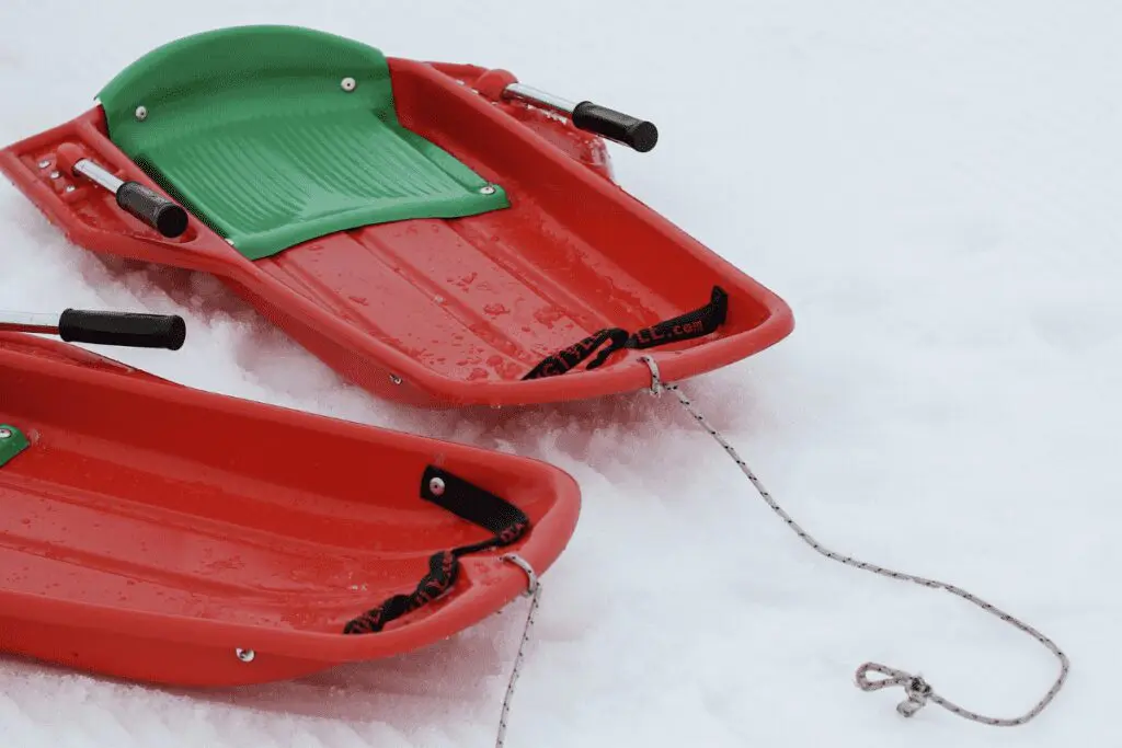 Two red and green sleds in the snow